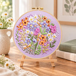Purple floral circle with dragonflies embroidery kit finished hoop displayed on a wooden stand as cozy tabletop decor
