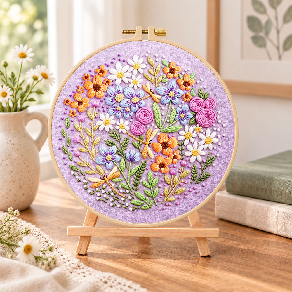 Purple floral circle with dragonflies embroidery kit finished hoop displayed on a wooden stand as cozy tabletop decor