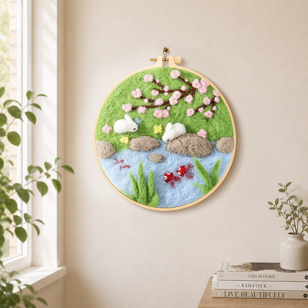 Rabbits fishing under cherry blossoms needle felt wall art displayed in a bright home interior