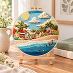 Radiant coastal hamlet embroidery kit finished hoop displayed on a wooden stand as cozy tabletop decor