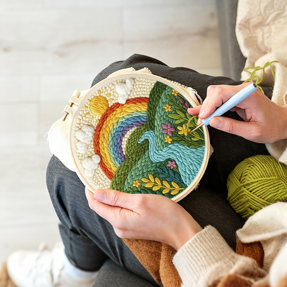 Creating handmade rainbow over the rolling river and green fields punch needle artwork