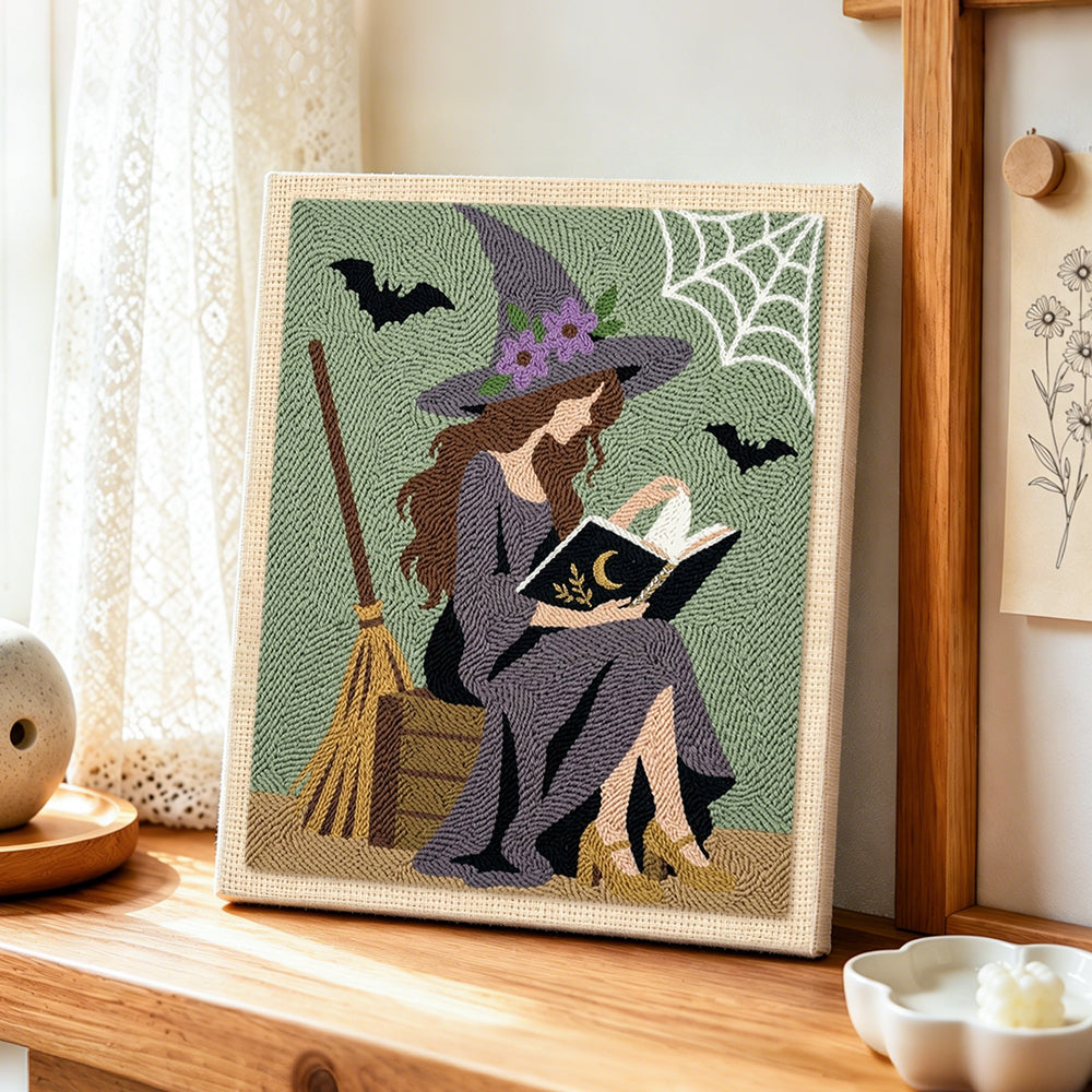 Reading witch with spell book punch needle artwork displayed on a table
