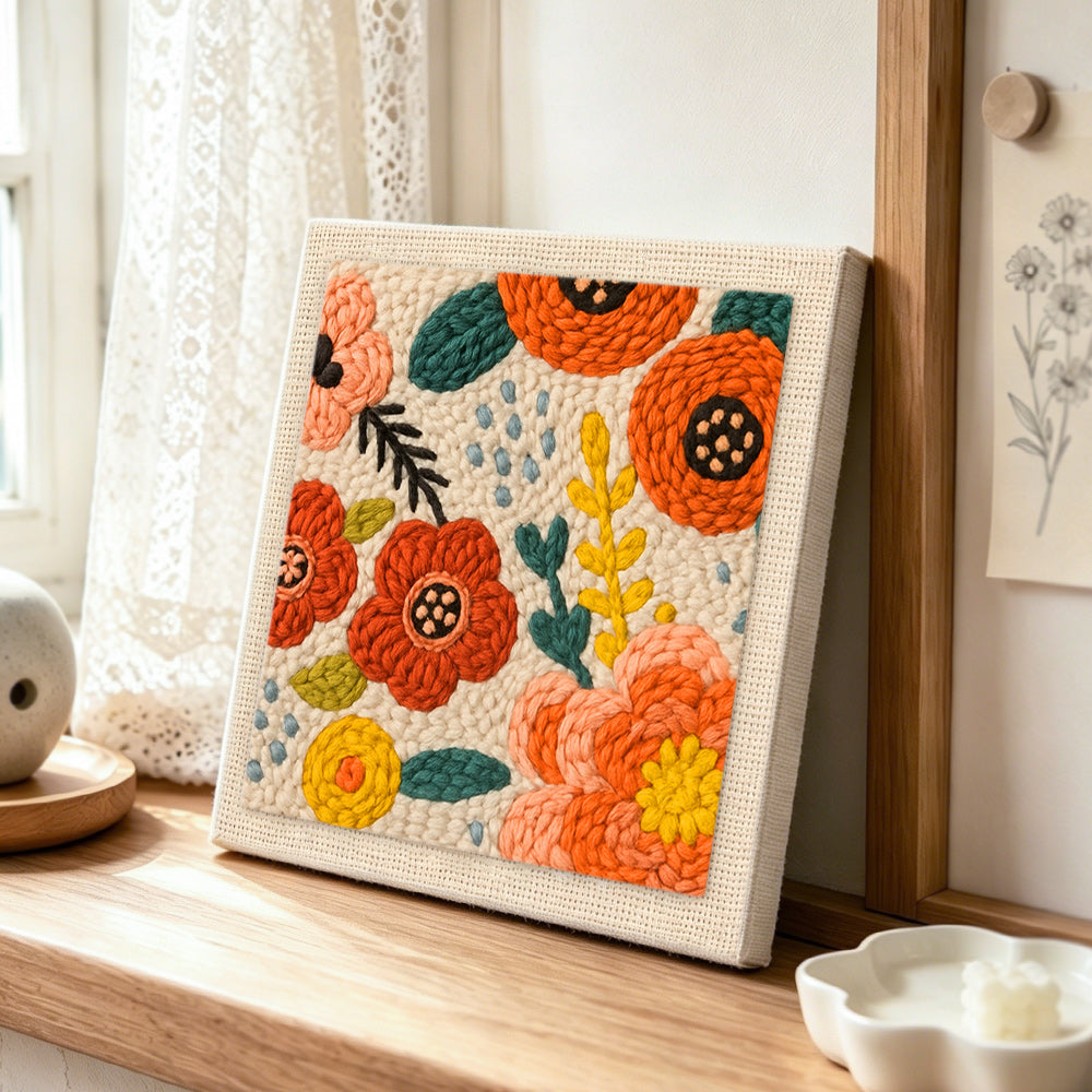 Red and orange flowers punch needle artwork displayed on a table