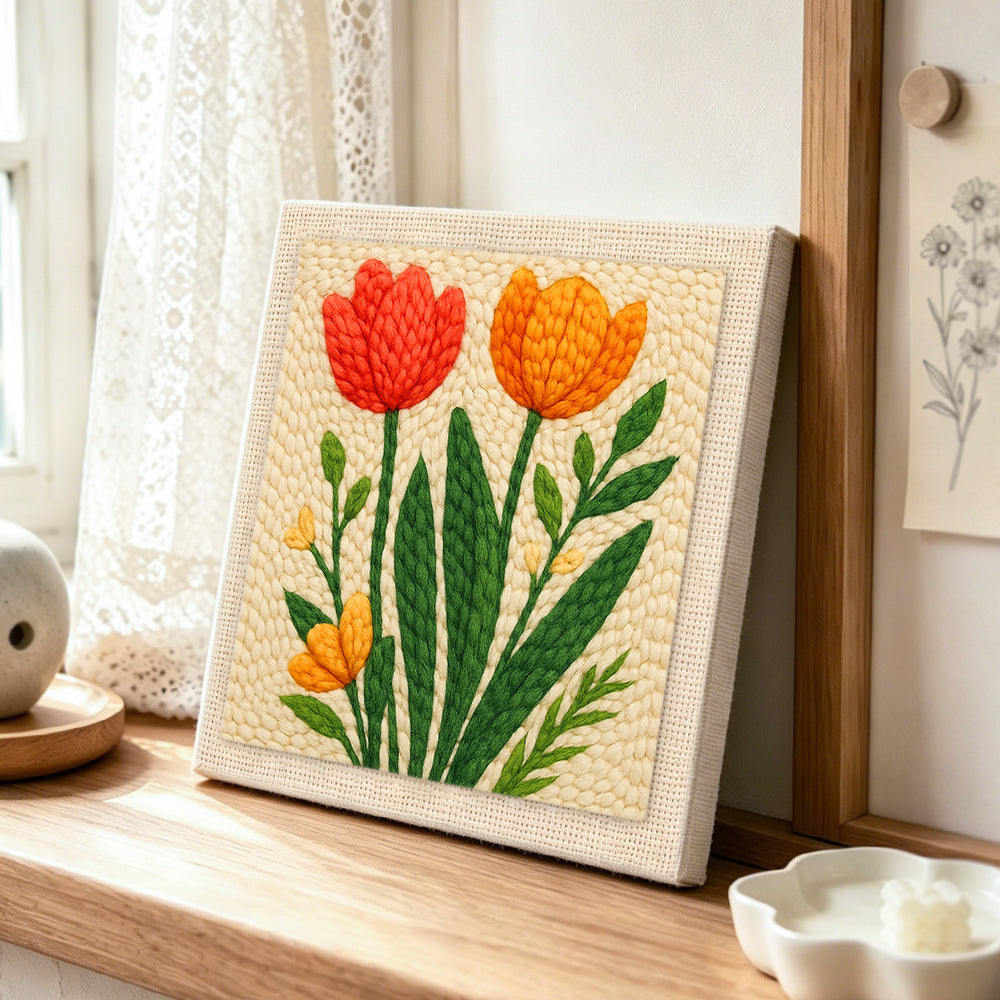 Red and orange tulips on the creamy background punch needle artwork displayed on a table