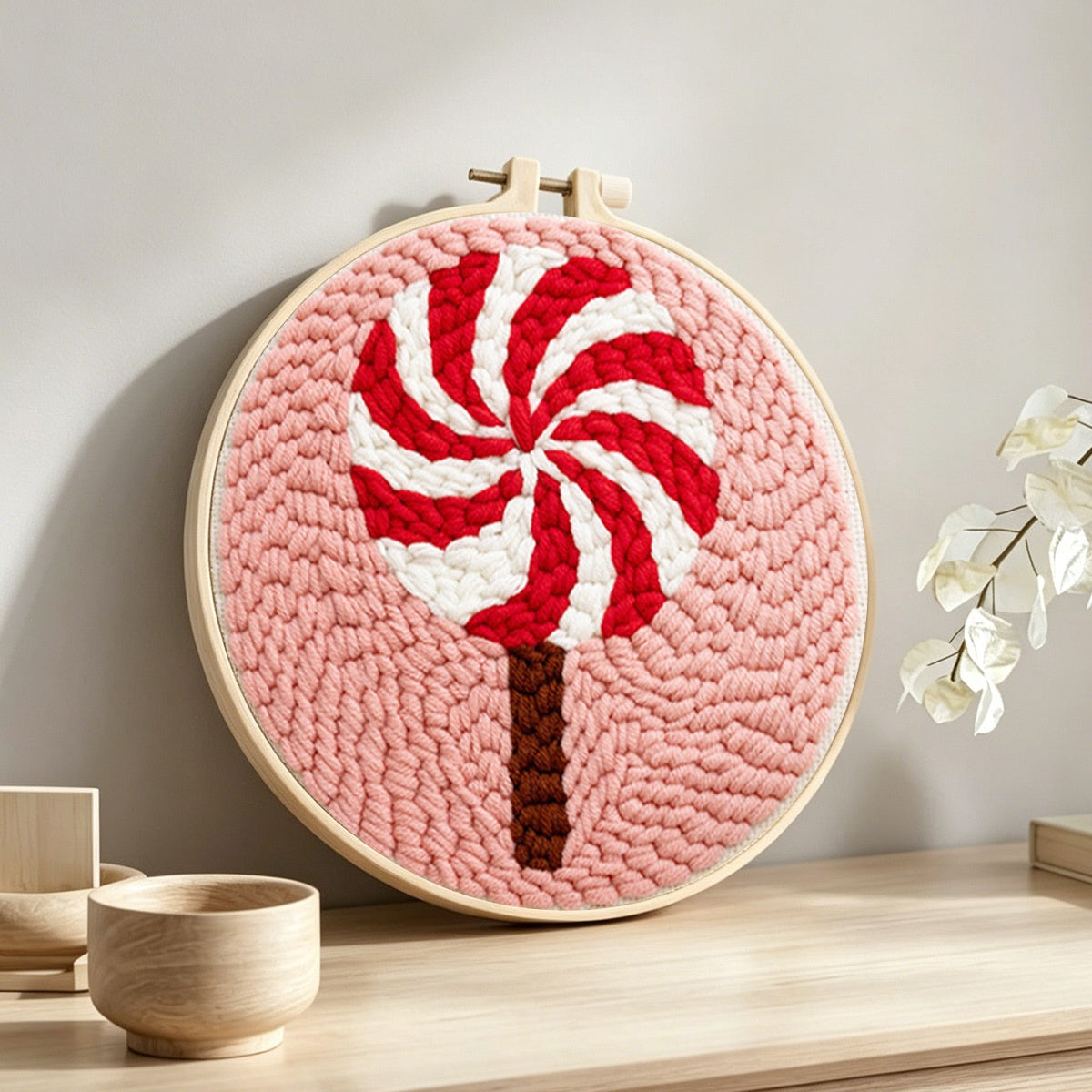 Red and white swirl lollipop punch needle artwork displayed on a table