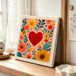 Red heart surrounded by colorful blooms punch needle artwork displayed on a table