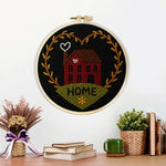 Finished red house with “home” heart wreath artwork displayed on a wall