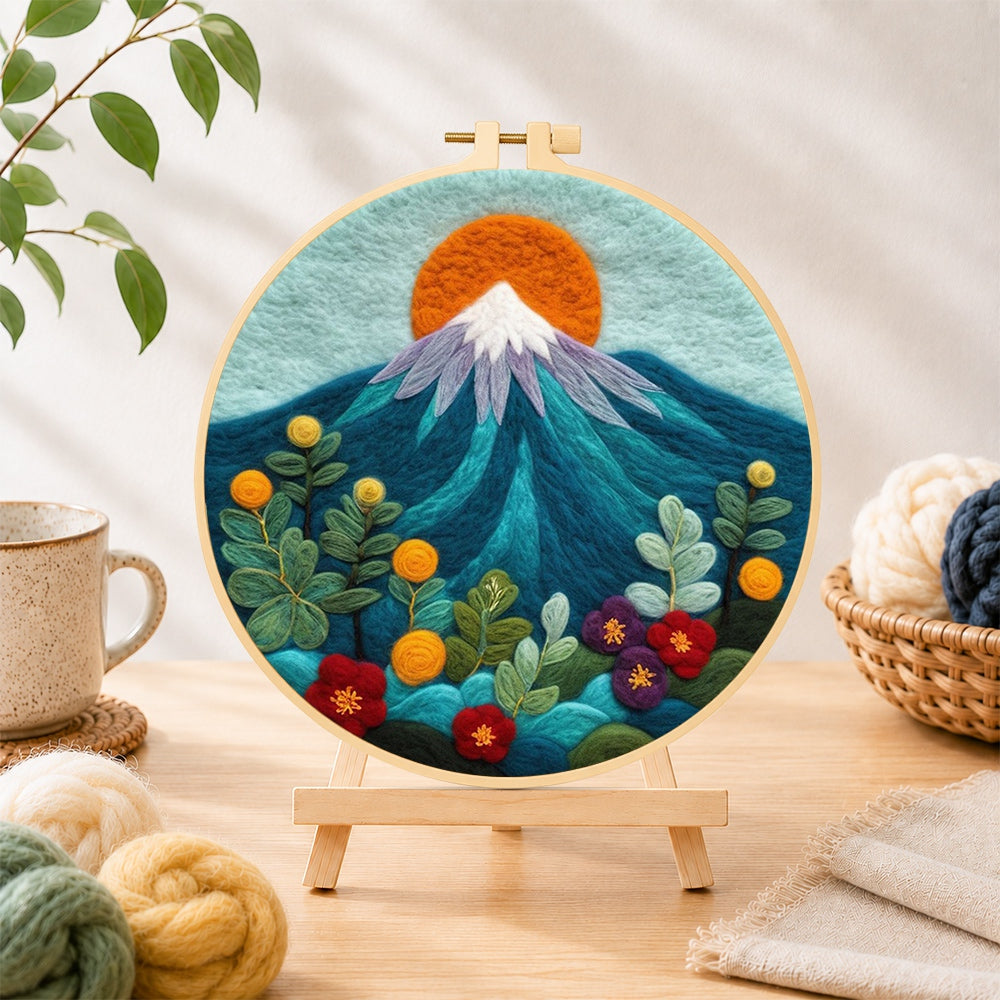 Finished red sun over snowy peaks needle felting displayed on a wooden easel