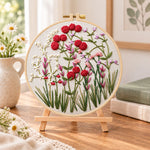 Red wildflower patch embroidery kit finished hoop displayed on a wooden stand as cozy tabletop decor