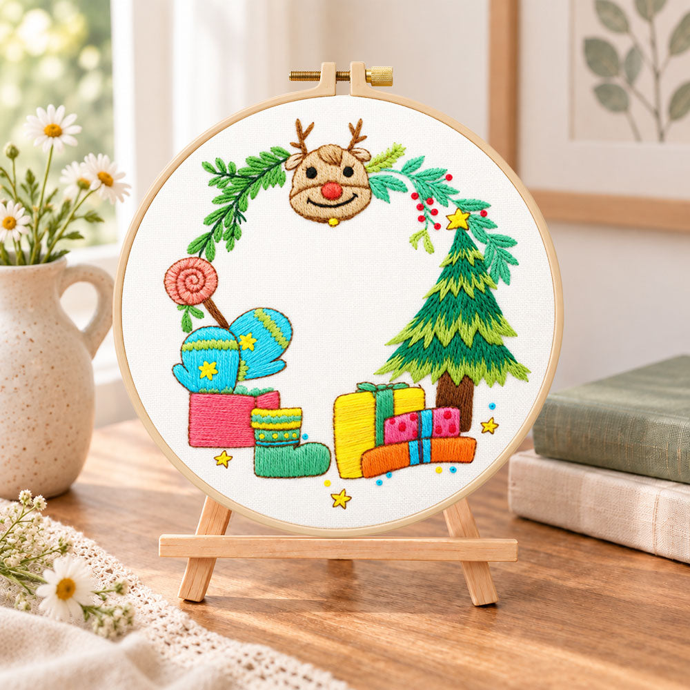 Reindeer and gifts scene embroidery kit finished hoop displayed on a wooden stand as cozy tabletop decor
