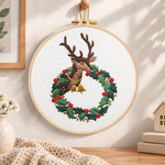 Reindeer in holly wreath embroidery hoop wall art displayed as warm and cozy handmade home decor