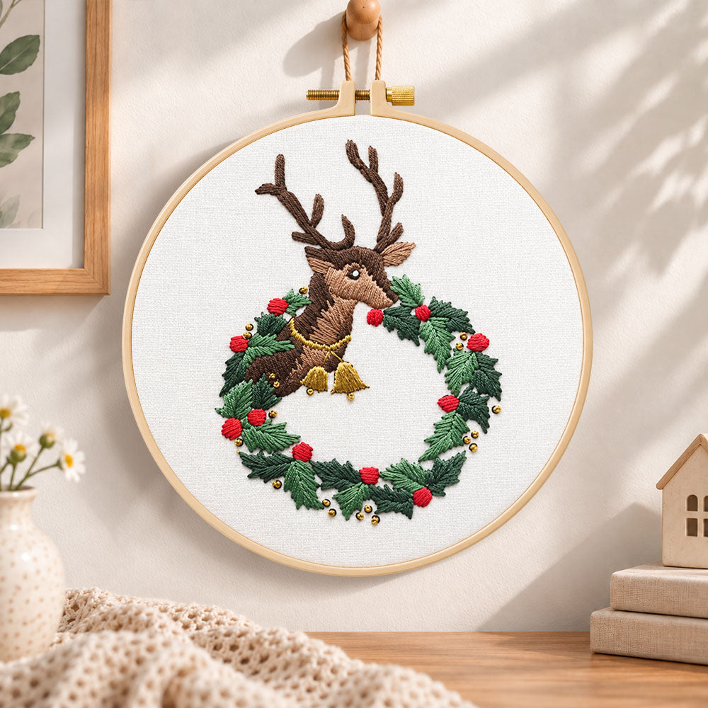 Reindeer in holly wreath embroidery hoop wall art displayed as warm and cozy handmade home decor