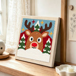 Rudolph reindeer face punch needle artwork displayed on a table