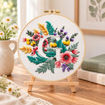 Rustic floral mix and letter g embroidery kit finished hoop displayed on a wooden stand as cozy tabletop decor