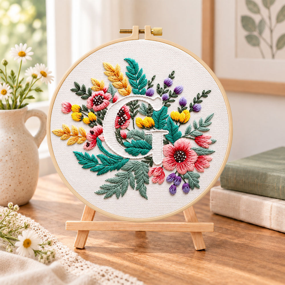 Rustic floral mix and letter g embroidery kit finished hoop displayed on a wooden stand as cozy tabletop decor