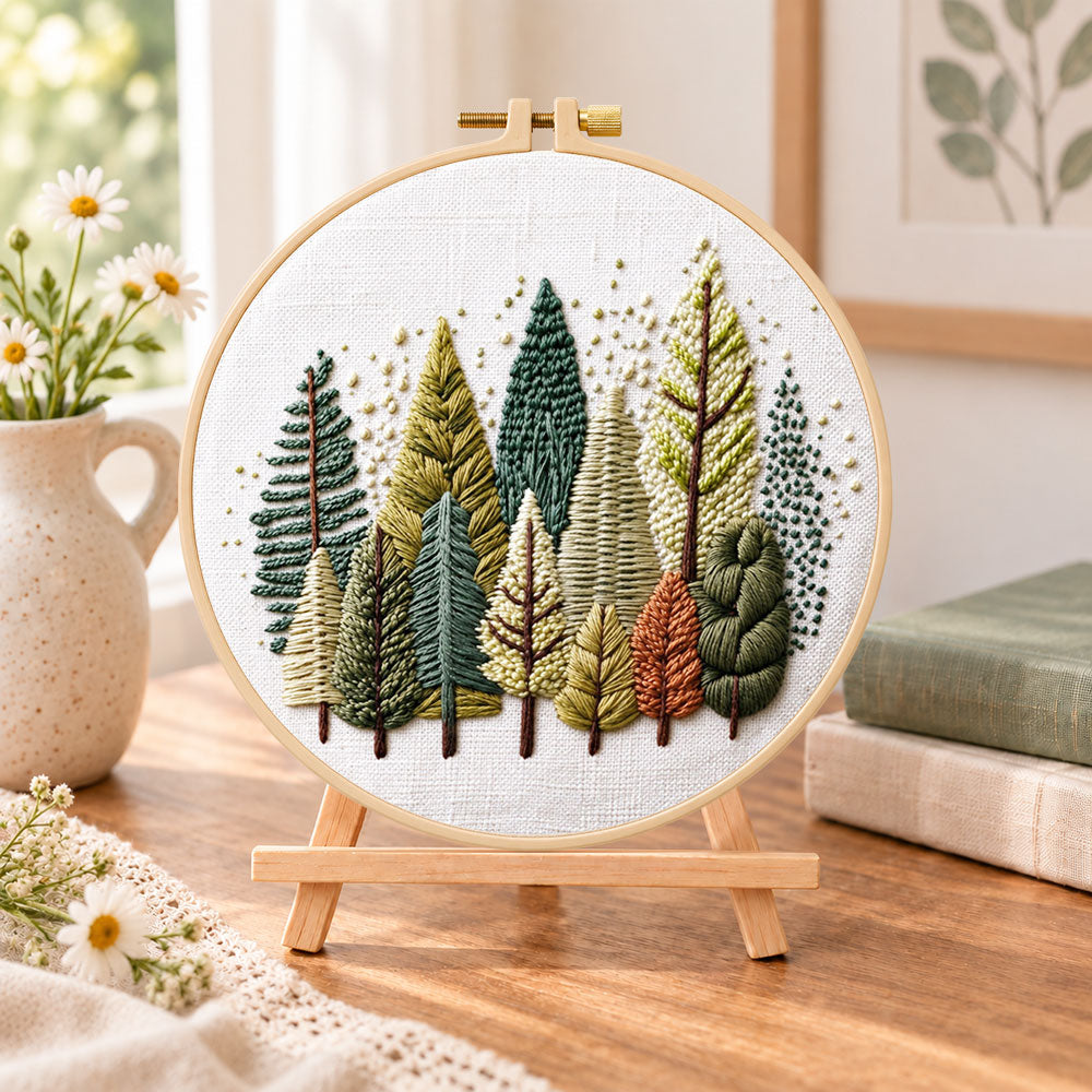 Rustic pine tree grove embroidery kit finished hoop displayed on a wooden stand as cozy tabletop decor