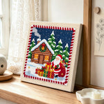 Santa and cabin christmas punch needle artwork displayed on a table