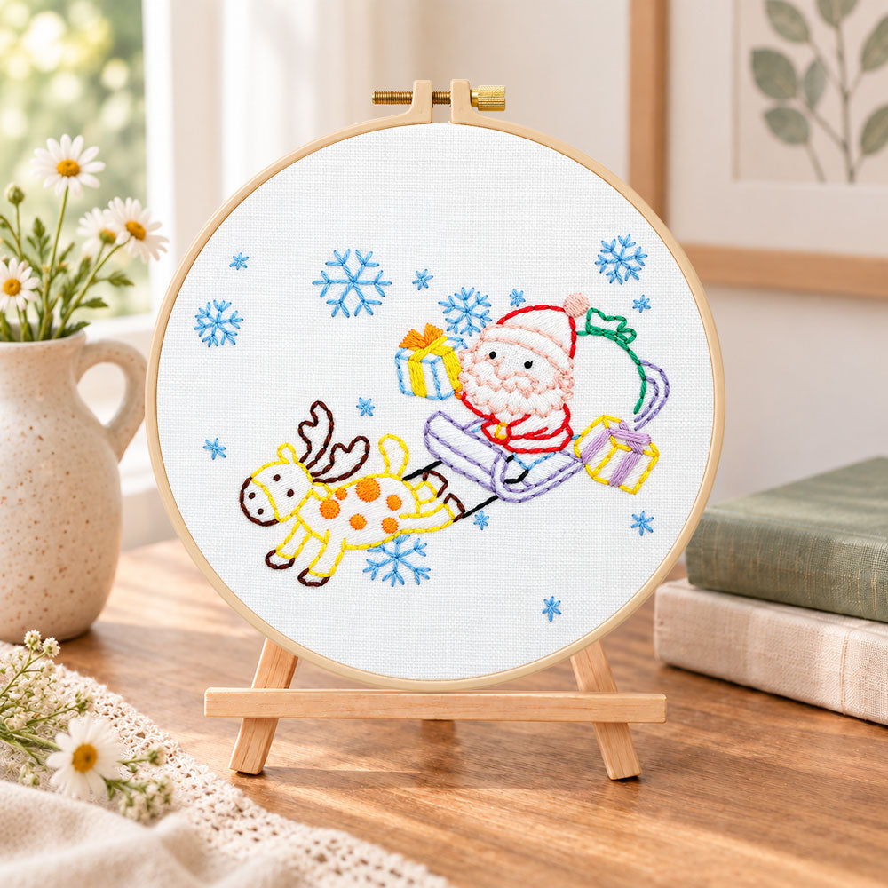 Santa sleigh ride embroidery kit finished hoop displayed on a wooden stand as cozy tabletop decor