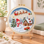 Santa sleigh winter village embroidery kit finished hoop displayed on a wooden stand as cozy tabletop decor