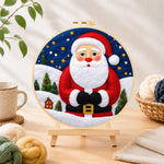 Finished santa with mini village needle felting displayed on a wooden easel