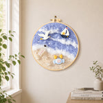 Seagull, crab and sailboat needle felt wall art displayed in a bright home interior