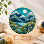Finished serene blue mountain with textured floral foliage needle felting displayed on a wooden easel