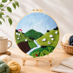Finished sheep on the green hillside needle felting displayed on a wooden easel