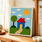 Simple sunny house and green tree punch needle artwork displayed on a table