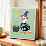 Skeleton duck with witch hat punch needle artwork displayed on a table