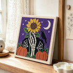 Skeleton hand sunflower halloween scene punch needle artwork displayed on a table