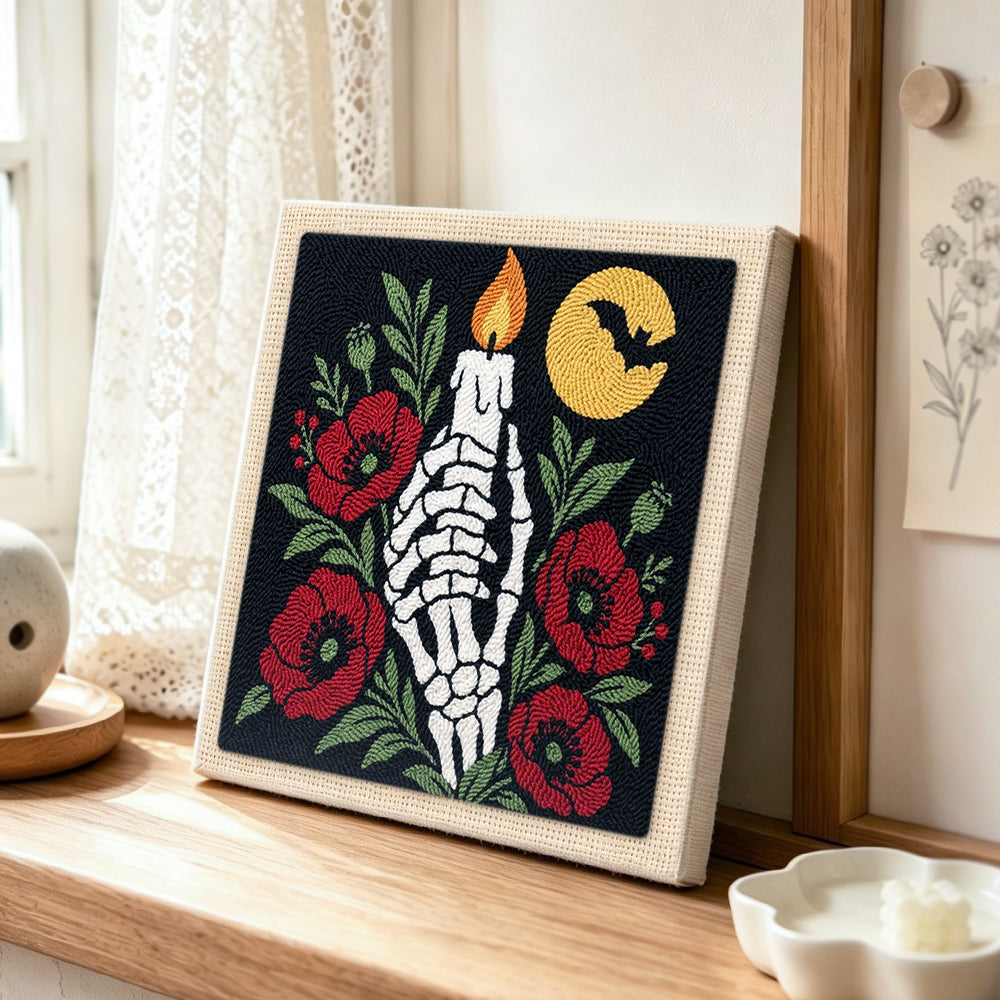 Skeleton hand with candle punch needle artwork displayed on a table