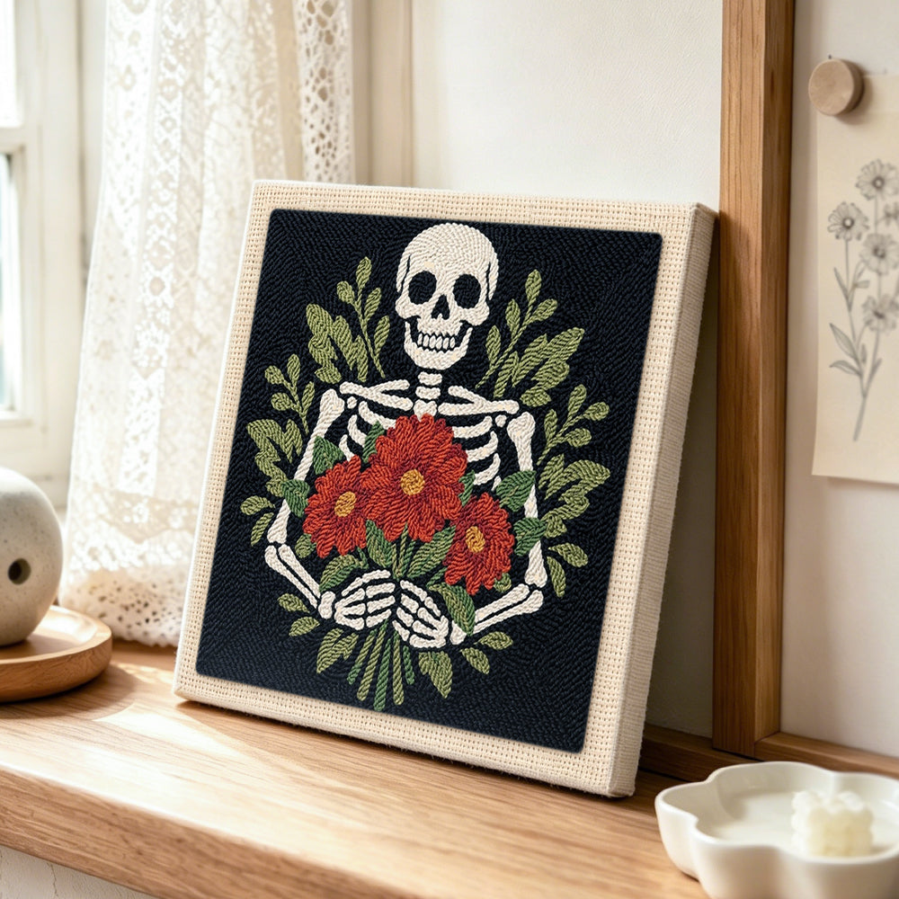 Skeleton holding red blooms punch needle artwork displayed on a table