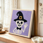 Skeleton in witch hat punch needle artwork displayed on a table