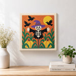 Finished skeleton scarecrow in pumpkin field artwork displayed on a wall