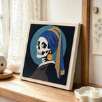 Skeleton with pumpkin earring punch needle artwork displayed on a table