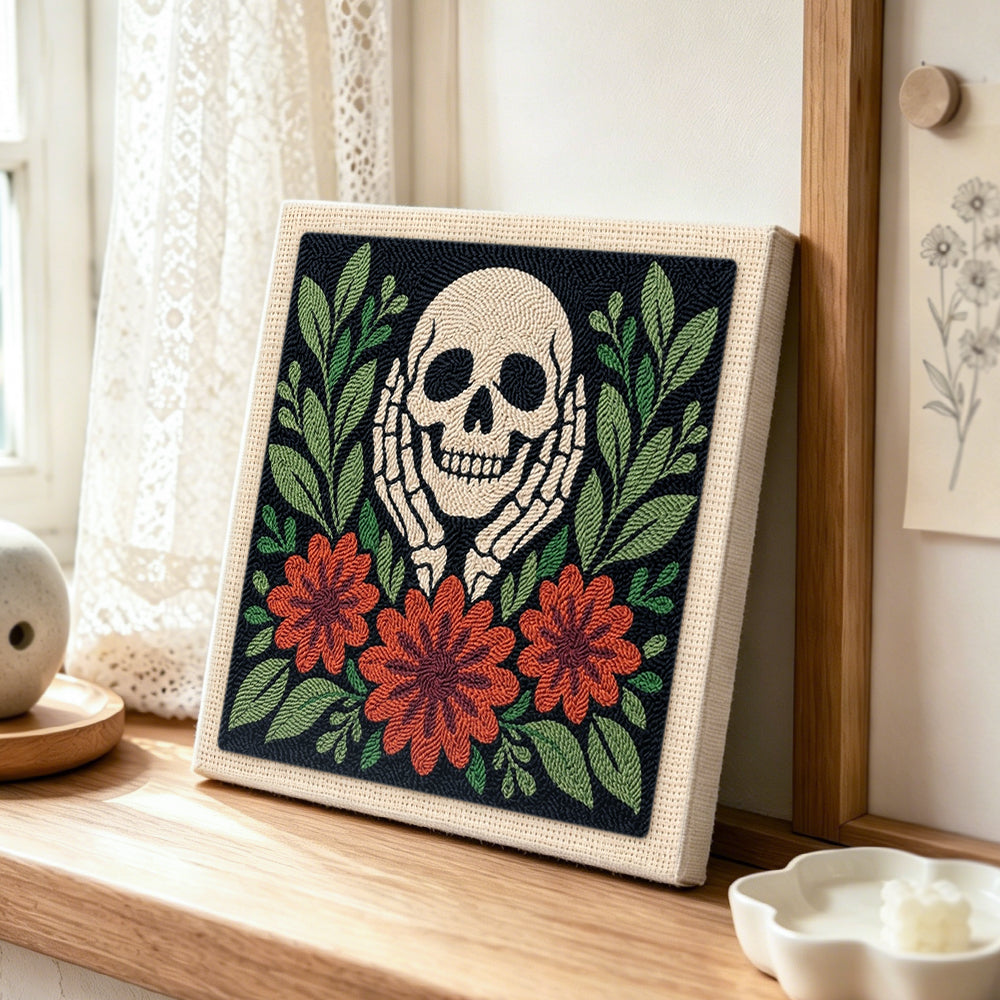 Skull cupping cheeks with autumn blooms punch needle artwork displayed on a table
