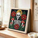 Skull with flowers and mushrooms punch needle artwork displayed on a table