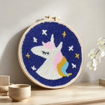 Sleeping unicorn under stars punch needle artwork displayed on a table