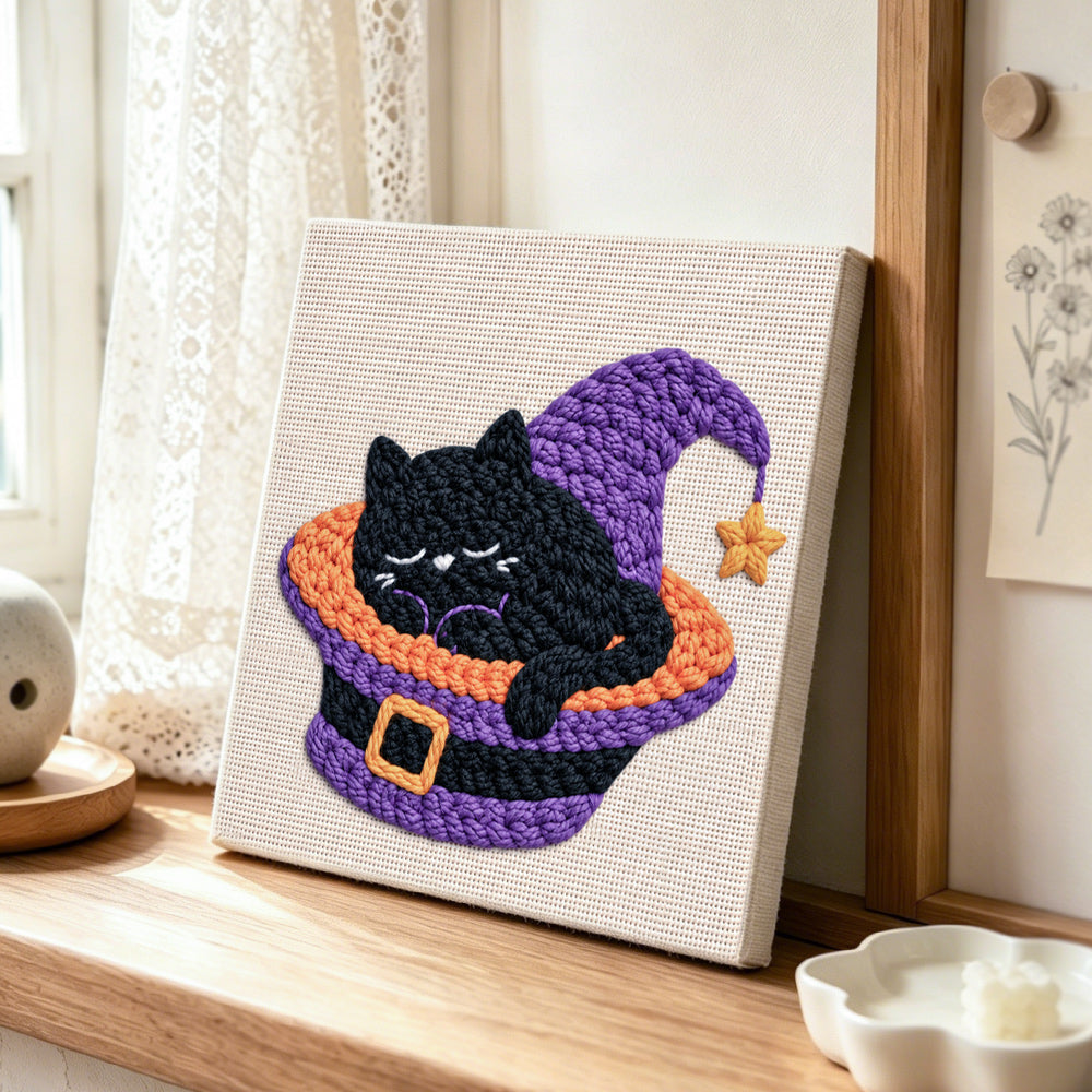 Sleepy black witch cat punch needle artwork displayed on a table
