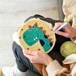 Creating handmade smiling green dinosaur punch needle artwork