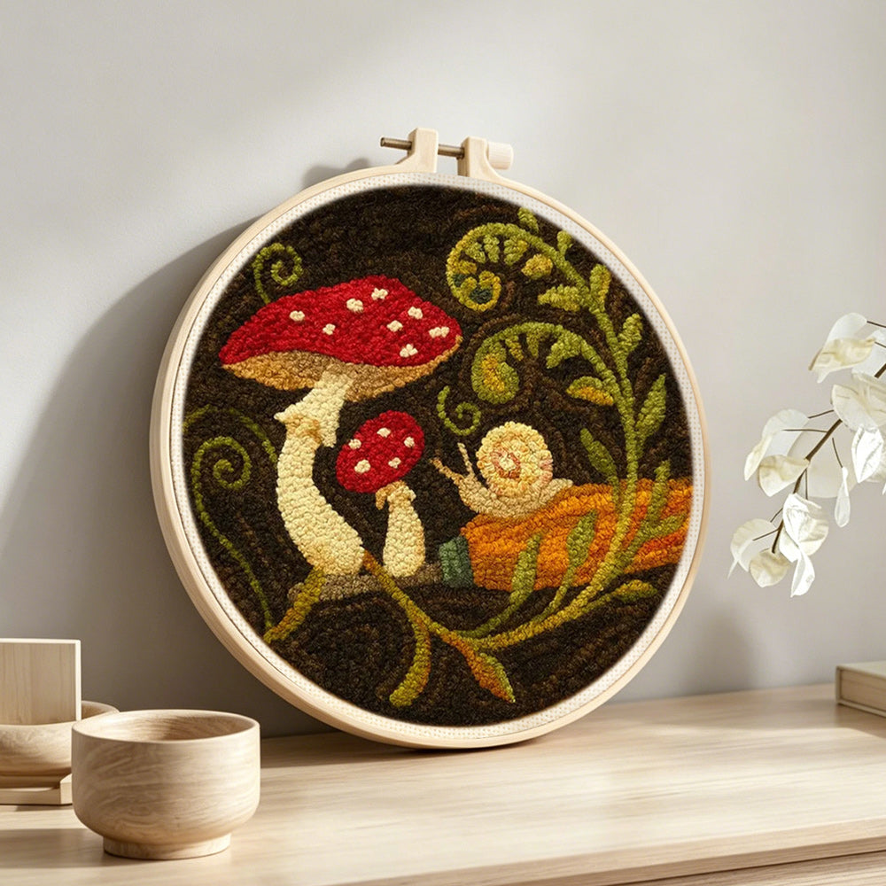 Snail and mushroom punch needle artwork displayed on a table
