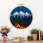 Finished snow-capped mountains, dark forest and campfire artwork displayed on a wall