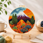 Finished snow-capped volcano and lush plants needle felting displayed on a wooden easel