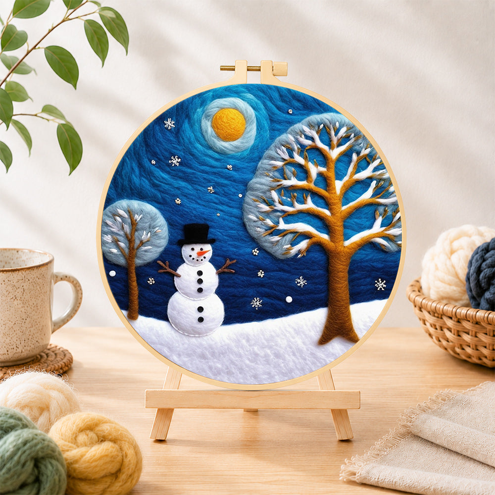 Finished snowman and frosted tree under the night sky needle felting displayed on a wooden easel