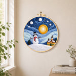 Snowman and swirling starry night sky needle felt wall art displayed in a bright home interior