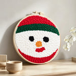 Snowman face punch needle artwork displayed on a table