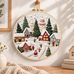Snowy christmas village embroidery hoop wall art displayed as warm and cozy handmade home decor