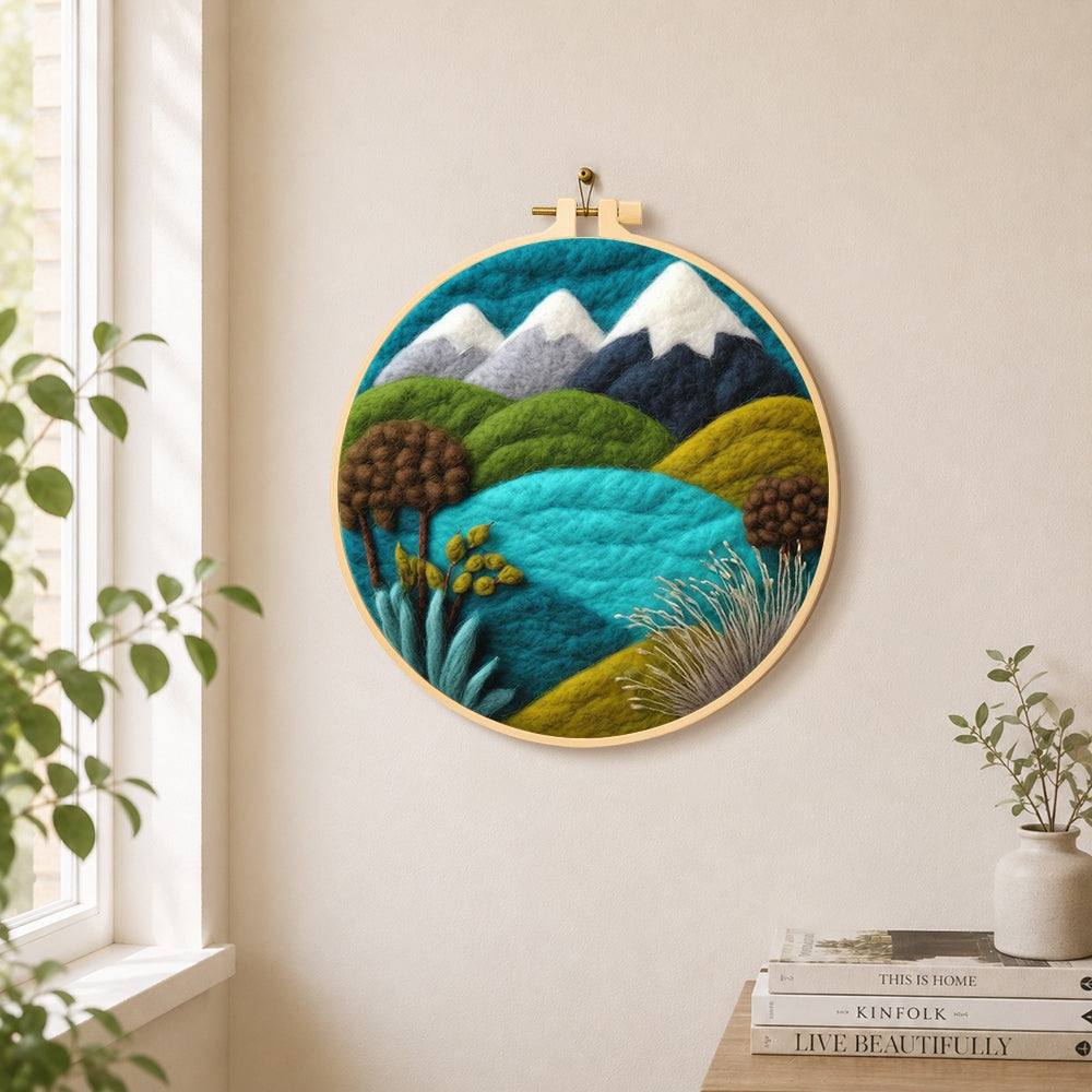 Snowy mountains and summer hills needle felt wall art displayed in a bright home interior