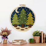 Finished snowy pine trees and crescent moon artwork displayed on a wall
