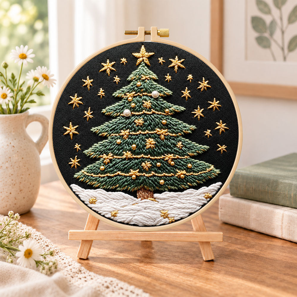 Snowy star christmas tree embroidery kit finished hoop displayed on a wooden stand as cozy tabletop decor